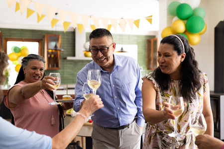 Senior friends celebrating with wine glasses at home, smiling and enjoying together. Celebration, friendship, togetherness, happiness, gathering, lifestyleの写真素材
