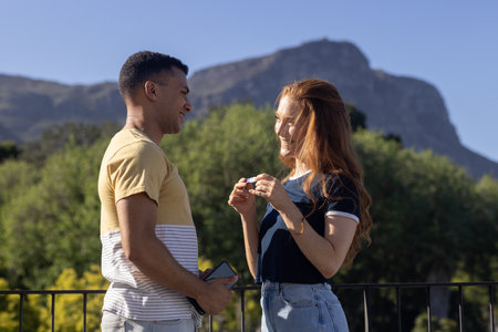Young couple enjoying conversation outdoors, smiling and holding smartphone together. Friends,...
