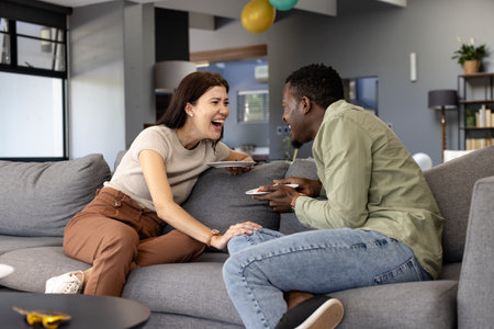 Laughing together, friends enjoying conversation on couch at home with tablets. technology, leisure, digital, entertainment, lifestyle, interactionの写真素材