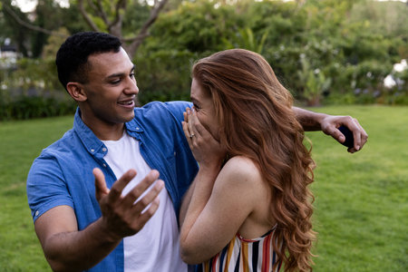 Young couple laughing and embracing in park, enjoying joyful moment together. Romantic, happiness, outdoors, affection, connection, togethernessの写真素材