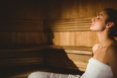 Wooden slatted benches glowing under warm side lighting inside sauna room, highlighting wood grain. Relaxation, wellness, serenity, natural, minimalist, interior, healthの写真素材