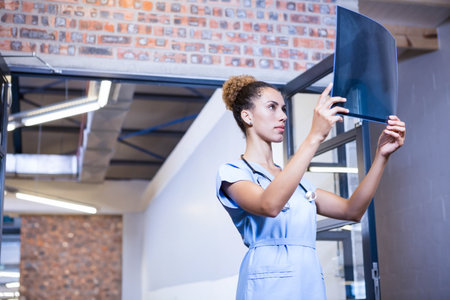 X-ray film being held up against light in clinical corridor, with brick wall and ductwork. Medical, diagnostic, industrial, healthcare, professional, clinical, analysisの写真素材