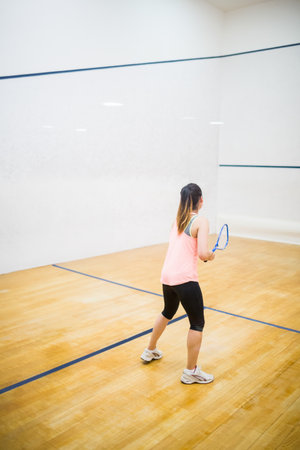 Squash racket is leaning against polished wooden floor in squash court, showing blue boundary lines.の写真素材