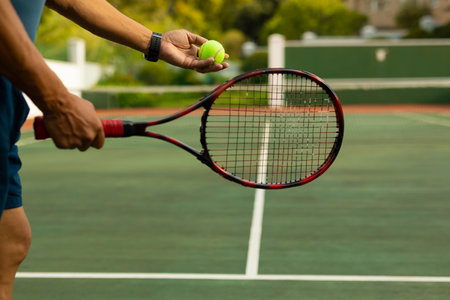 Senior male tennis player standing preparing serve on baseline court with racket, ball, copy space. Athletic, outdoor, recreational, vintage, competitive, landscape, activeの写真素材