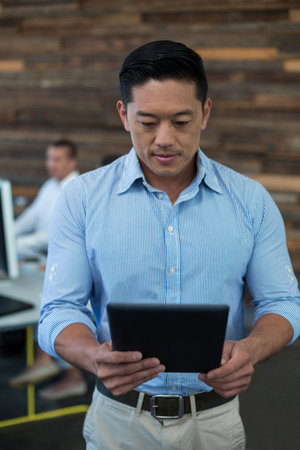 Diverse coworkers standing and sitting at desks in modern office using tablet and desktop computers. Collaboration, technology, professional, workspace, modernity, productivity, teamworkの写真素材