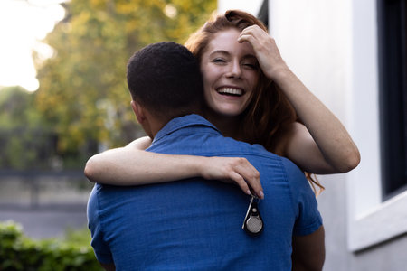 Young couple embracing outdoors, woman smiling joyfully while holding keys. love, happiness, romance, new home, lifestyleの写真素材