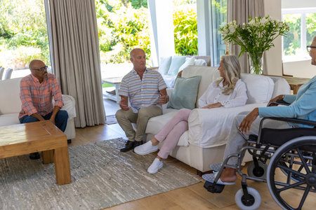 Diverse senior friends chatting in living room around wooden coffee table and wheelchair on rug....