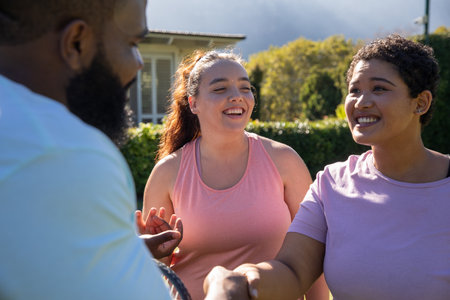 Diverse friends wearing sportswear playing tennis on front lawn using tennis rackets. Fitness,...