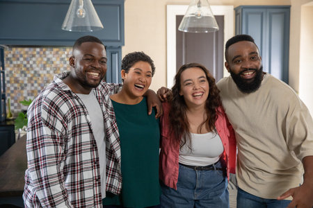 Diverse friends standing in kitchen beside island with mosaic backsplash, houseplant under pendants....