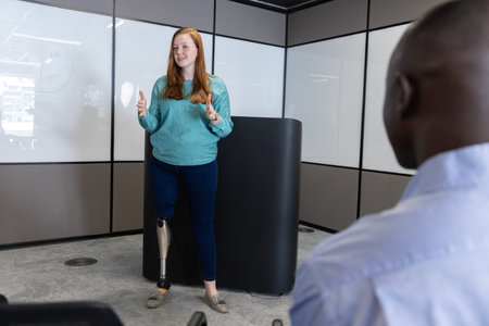 Diverse coworkers presenting at office lectern with whiteboard panels and visible prosthetic leg....