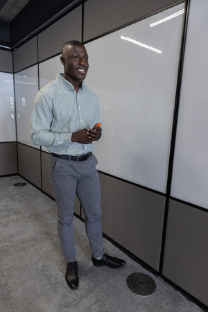 African American man presenting on whiteboard in boardroom with orange black markers, copy space....