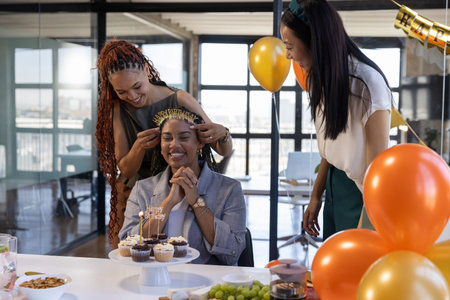 Diverse coworkers celebrating birthday in office conference room with cupcake stand and tiara. Festivity, diversity, professionalism, celebration, modernity, teamwork, eleganceの写真素材