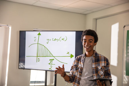 African American man holding tablet, gesturing to screen showing cos graph in classroom, copy space....