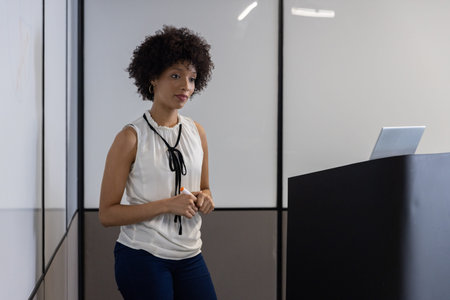 African american woman teaching on whiteboard podium using marker, laptop in boardroom, copy space....