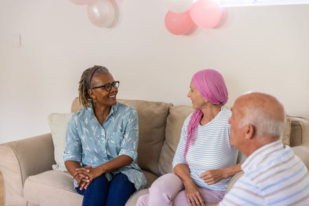 Diverse senior friends chatting on beige couch in living room at home with balloons and pillow....