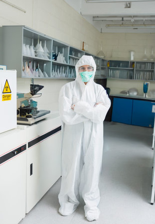 Clinical lab is showing full white protective suit centered, microscope and biohazard cabinet....