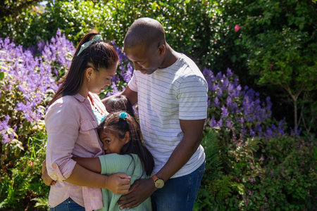 Diverse family embracing in backyard garden surrounded by green foliage and purple flowering shrubs. Family, togetherness, nature, tranquility, harmony, outdoor, botanicalの写真素材