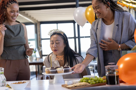 Diverse coworkers gathering at office meeting room celebrating birthday with cupcakes and balloons. Professional, celebration, festive, modern, teamwork, decor, socialの写真素材