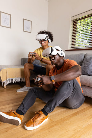 Diverse male friends playing VR in living room wearing white VR headsets and holding controllers....