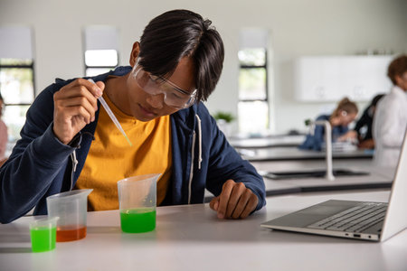 Diverse classmates conducting science experiment using plastic dropper and beakers at lab bench. Scientist, collaboration, education, innovation, research, technology, teamworkの写真素材