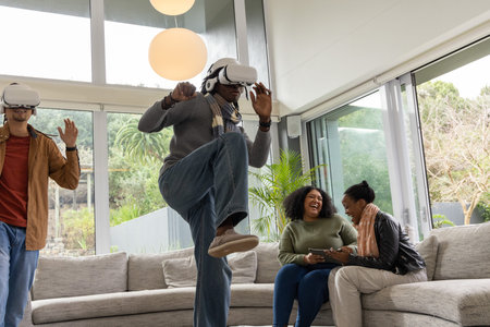 Diverse friends using white VR headsets and interacting with tablet in modern living room. Virtual, devices, lounge, interior, contemporary, daylight, gardenの写真素材