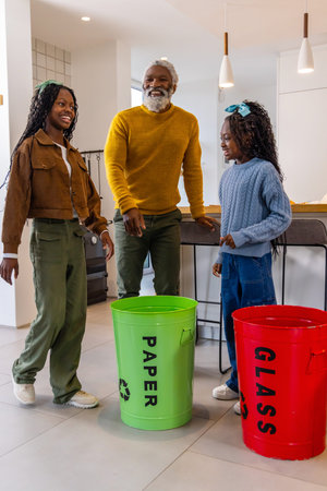 African American family sorting PAPER and GLASS bins in kitchen, senior wearing mustard sweater....