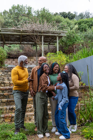 African American family standing on yard by stone steps and wooden pergola wearing sweaters. Multigenerational, outdoor, garden, terrace, arbor, hillside, greeneryの写真素材