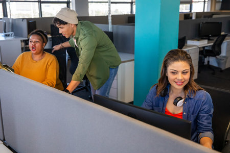 Diverse coworkers helping at open office with monitors, denim shirt, headphones, copy space....