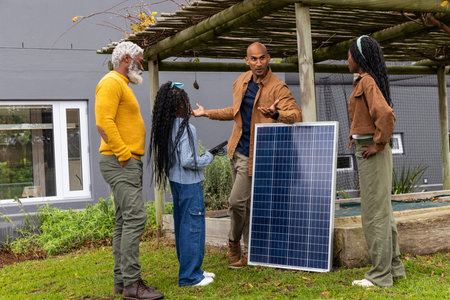 African American family at pergola, teen nearby, child holding tablet, man gesturing by solar panel....