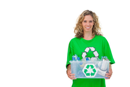 Midlife woman wearing green recycle shirt holding clear tote of bottles and cans studio, copy space. Sustainability, ecofriendly, environmental, minimalist, containers, awareness, advertisingの写真素材