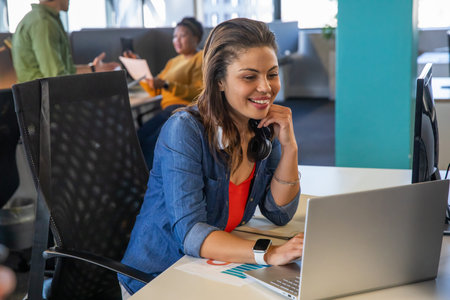Woman working on a laptop in a modern office with her team