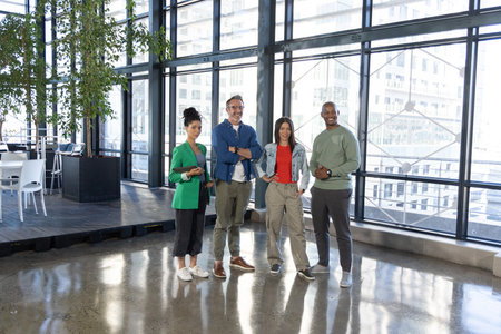 Diverse coworkers standing in modern office near windows, with smartphone, eyeglasses, wristwatch. Teamwork, collaboration, professionals, coworking, workspace, modern, cityscape