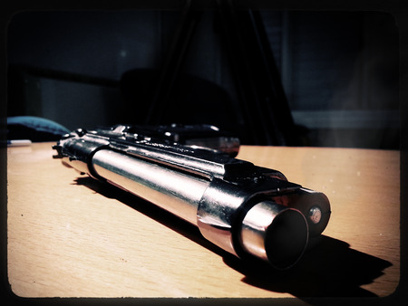Silver 9mm pistol lying on a wooden table. Smoke coming from the barrel of the gun.の写真素材