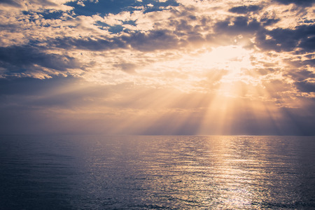 A beautiful sunset over the sea. Sunbeams are shining through the clouds.の写真素材