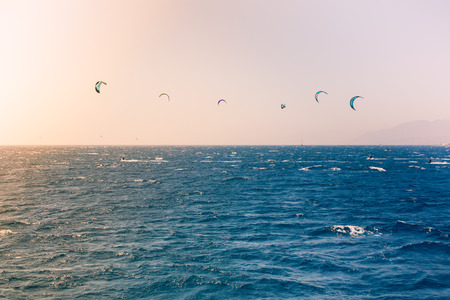 Windsurfers sailing in the Red Sea. Near the beach of Eilat Israel. Bright orange light coming from the sun on the left.の写真素材