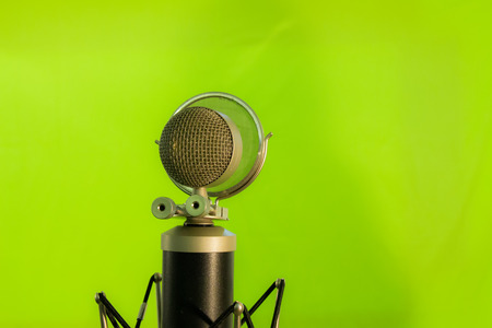 Close up of a vocal condenser microphone with wind screen isolated on green background.の写真素材