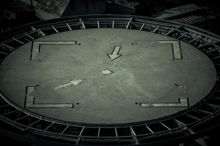 Concrete helicopter landing pad on the top of a building. Shapes of arrows in a square inside a circle.の写真素材