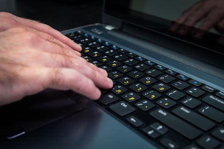 Man typing on a keyboard with letters in Hebrew and English - Laptop keyboardDark atmosphere