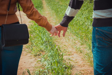 Young couple holding hands on the background of green grassの写真素材