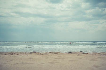 Adult man in the water at the beach on a cloudy day.の写真素材