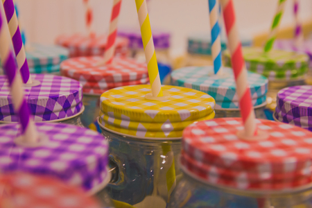 Many jars with colorful lids and drinking straws.の写真素材