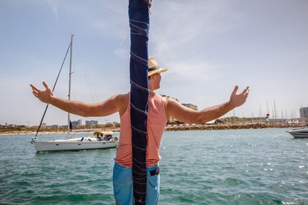 Man standing on a bow of sailboat with arms raised.の写真素材