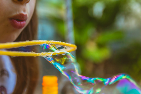 Close up of little girl blowing soap bubbles.の写真素材