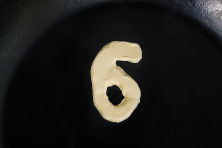 Butter in shape of number 6 on hot pan - Close up top view.の写真素材
