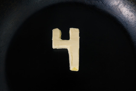 Butter in shape of number 4 on hot pan - Close up top view.の写真素材