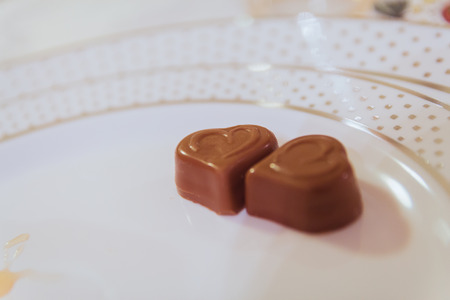 Closeup of two heart shape chocolates on white plate.の写真素材