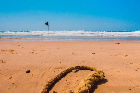 Black warning flag marking the limit of the safe swimming area at a beautiful beach with blue sky and a turquoise sea in israel.の写真素材