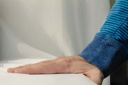 Man leaning and puts his hands down on white cloth background.の写真素材