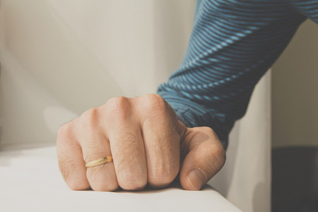 Man with a wedding ring squeezed his hand on white cloth background.の写真素材