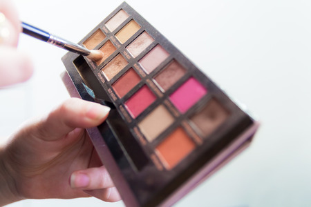Close up of woman hands holding colorful makeup eye shadow palette.の写真素材